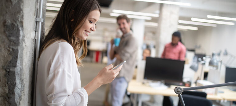 A smiling woman on her phone in an office