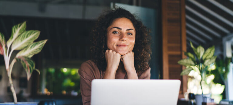 A woman working at a laptop, smiling at the camera