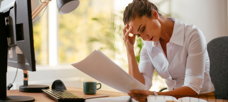 A woman with her head in her hands, holding an invoice