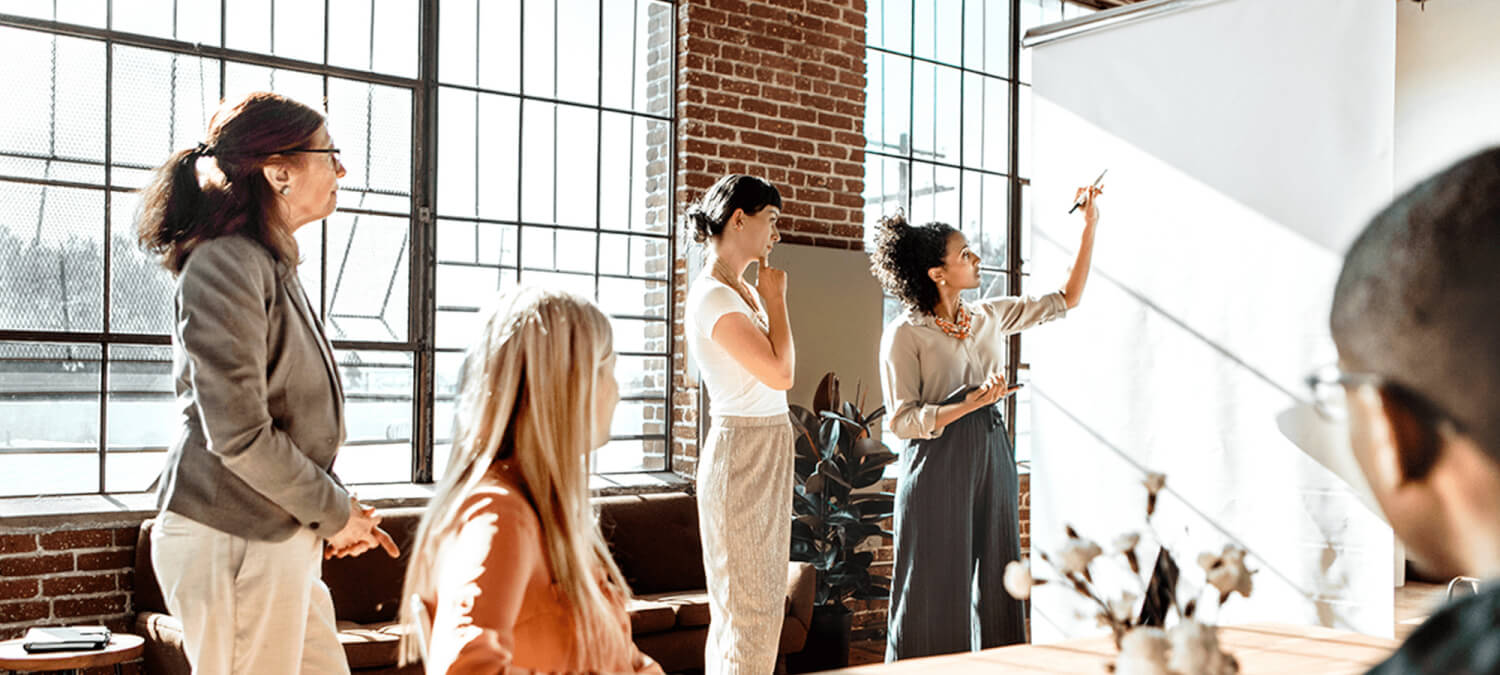 A group of people having a workshop, looking at a whiteboard