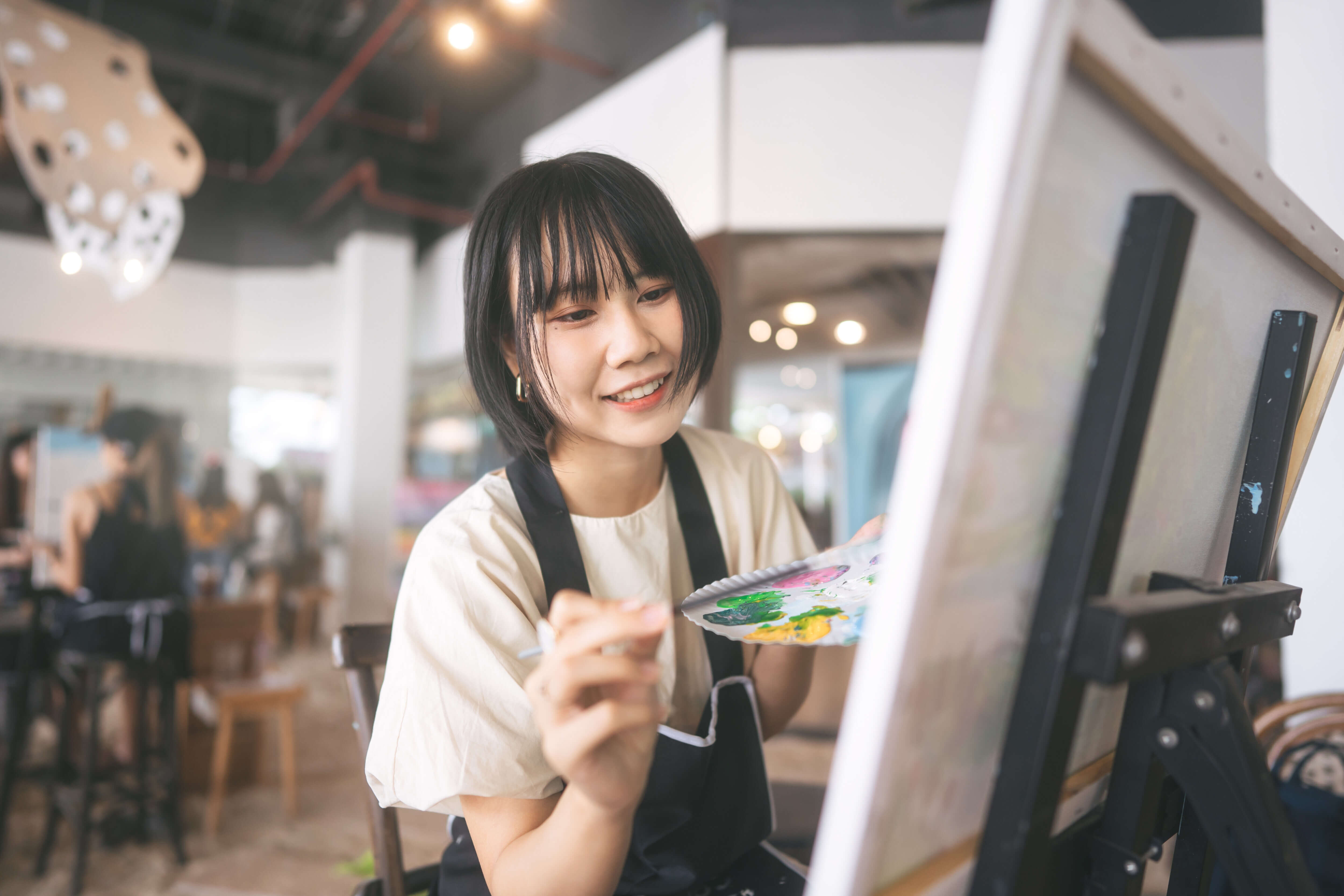 Portrait of happy young adult business woman painting brush on canvas at workshop art lesson class. People leisure with creativity education lifestyle for mental health concept.