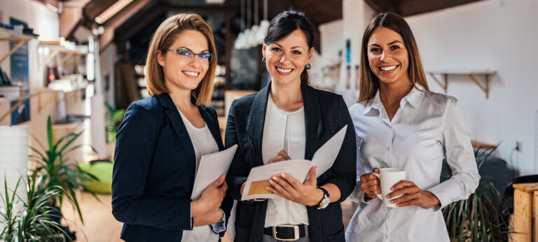 three business women standing smiling