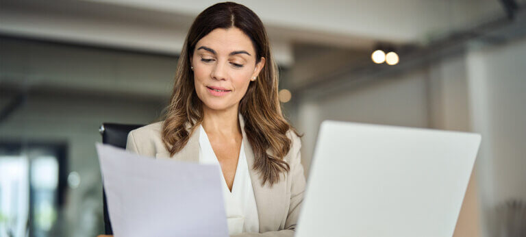 business woman sitting on pc, looking at invoice