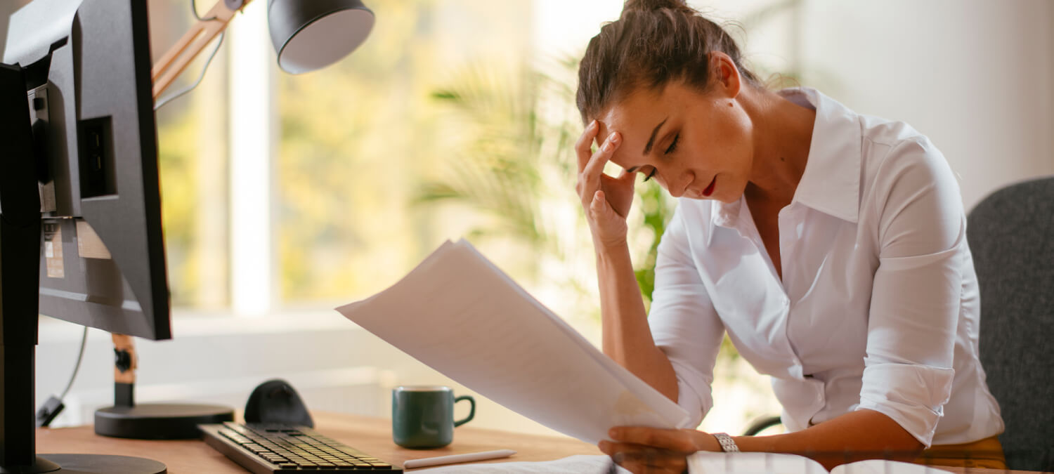 A woman studying a disputed invoice with her head in her hands