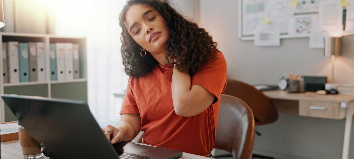 a woman sitting at a desk touching her shoulders