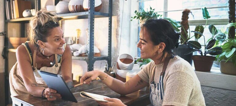 Two smiling women working in a pottery studio in Indonesia