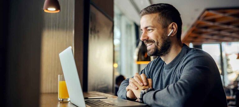 A smiling man working on a laptop
